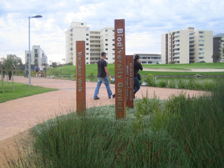 two people walking next to a sign near grass and building