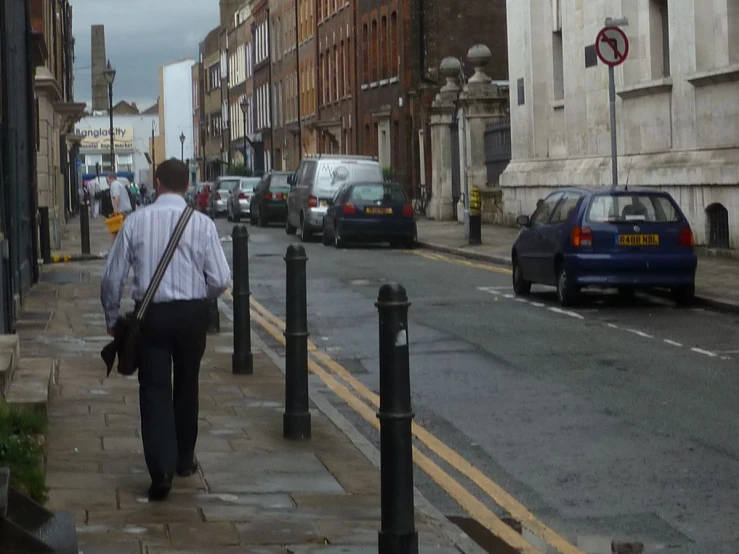 a man is walking down the street while he is using his phone