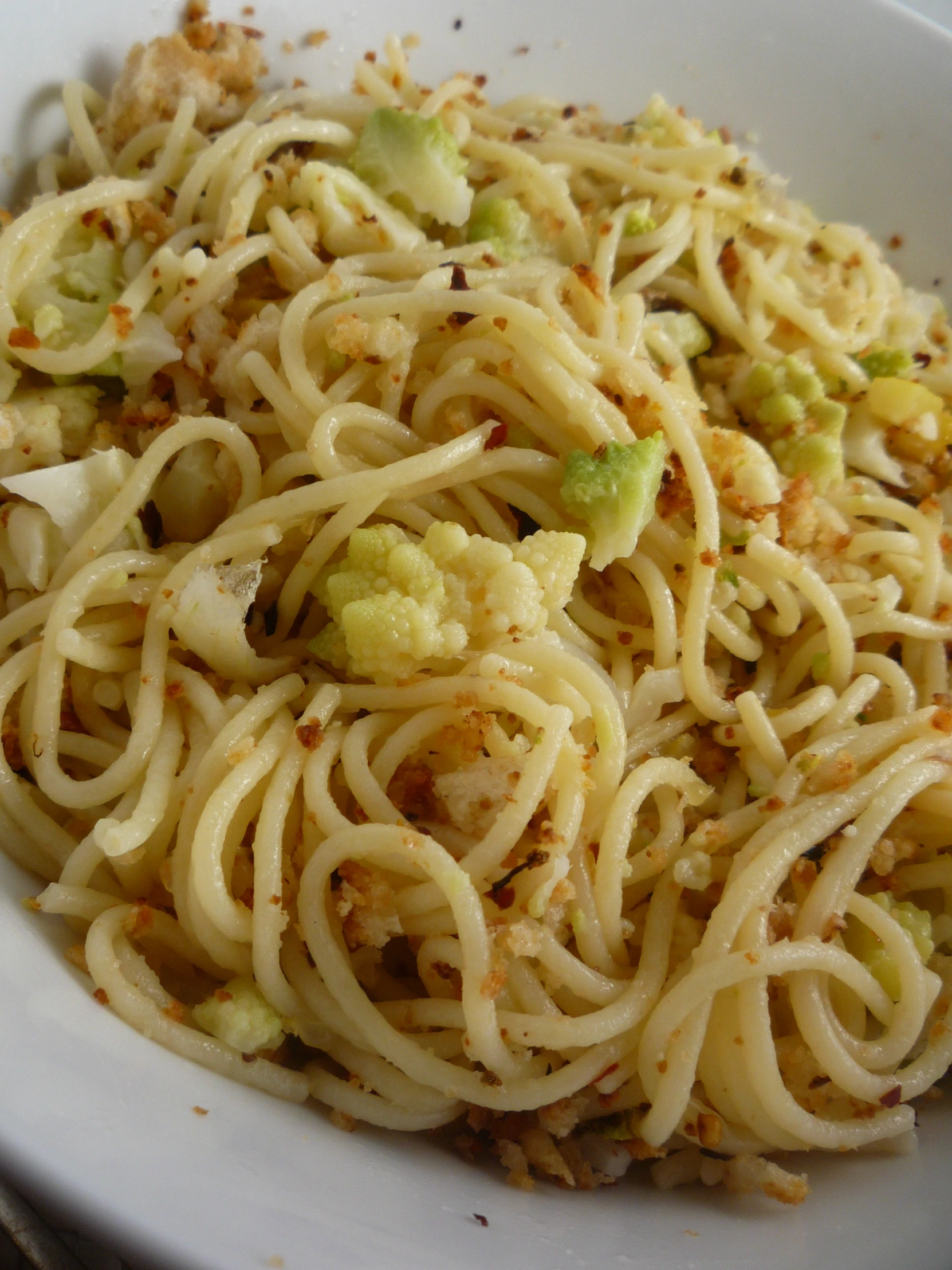 a plate of pasta with broccoli and seasoning