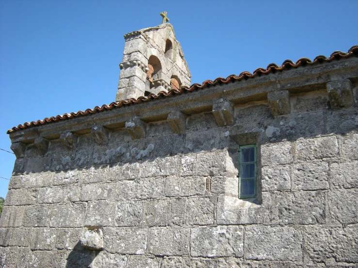 an old stone building has a large tower and cross on it