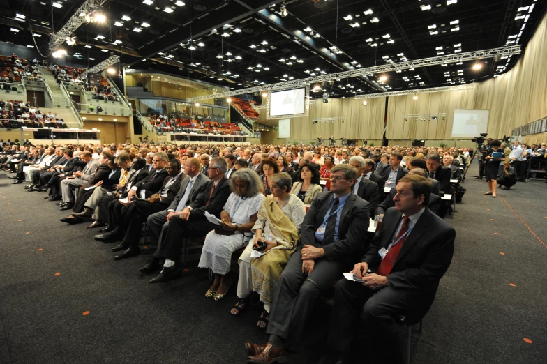 a large group of people sitting in chairs watching soing