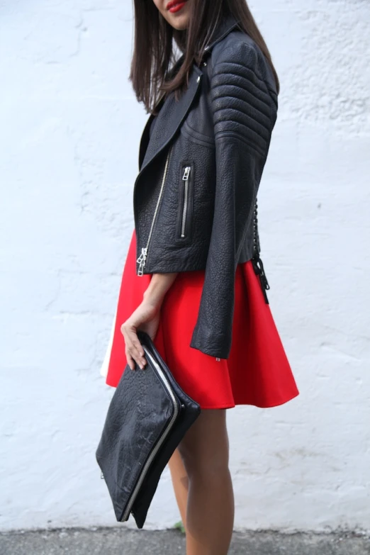 a young woman with her hand on a purse wearing a red skirt