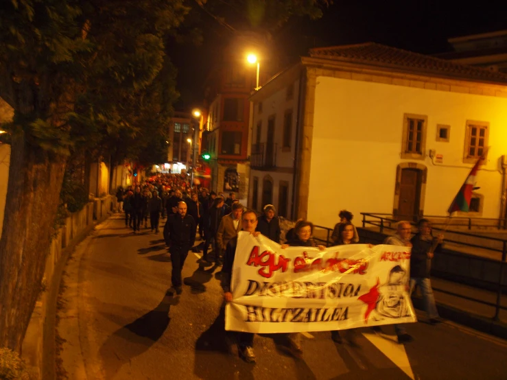 people walk on the street carrying a large sign