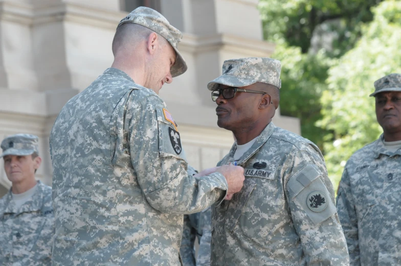 a military man is adjusting another person's uniform