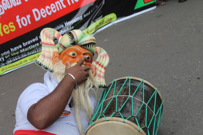 a person in face paint playing a game of drum