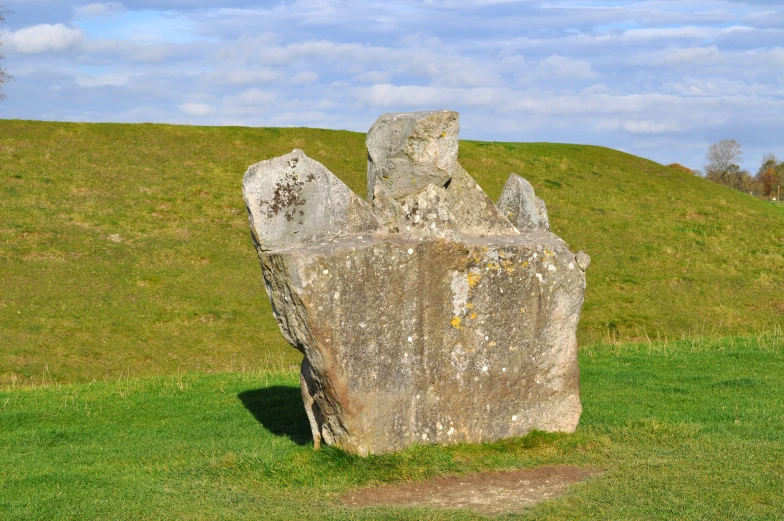 large stone sculpture in grassy field under blue sky