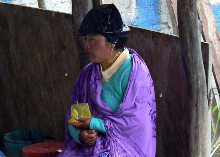 a woman in blue sitting next to a wooden wall