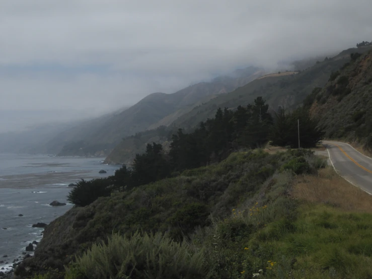 fog rolls in over a highway with a lush green landscape