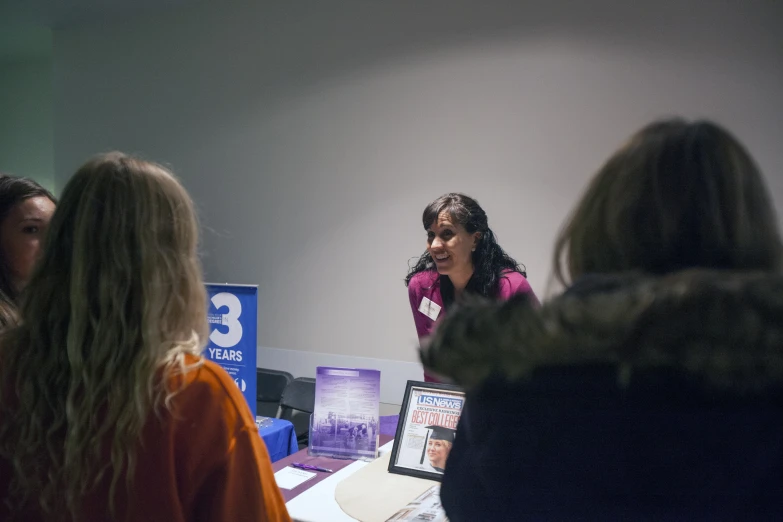 a woman in a purple jacket talking to some people