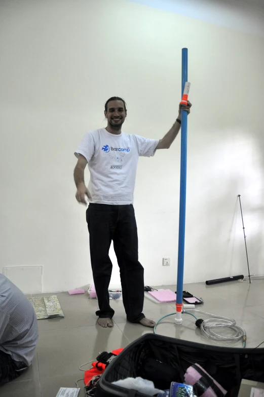 a man standing on a floor holding up a blue pole