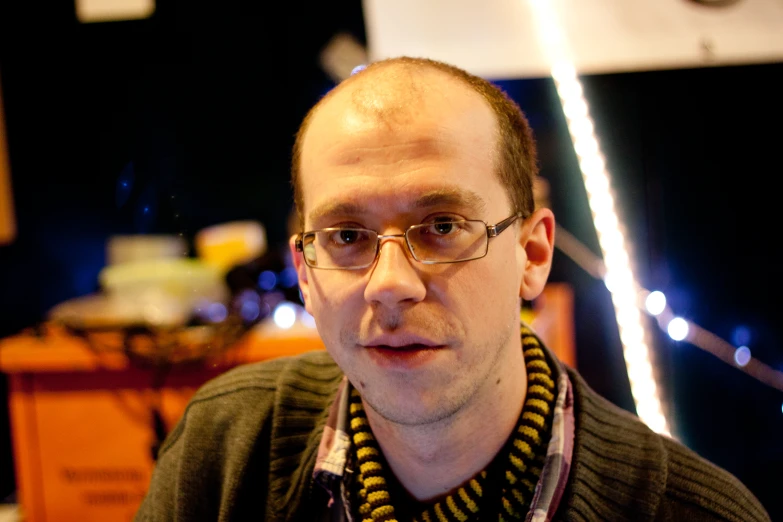 man wearing glasses looking into the camera with blurred background