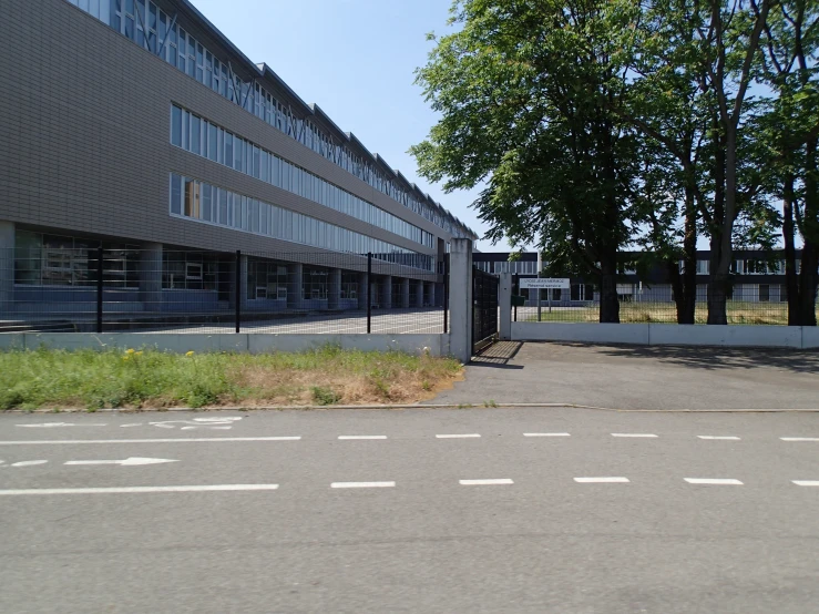 an empty parking lot is near a building and trees