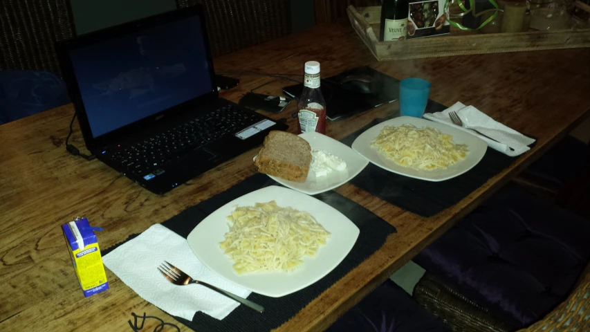 a table with two plates filled with food next to laptop computer