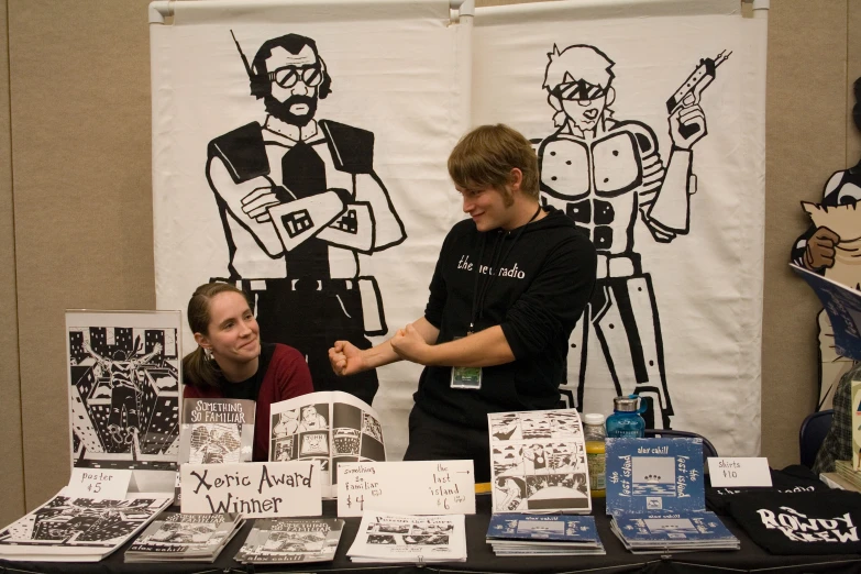 a couple of people stand at a table with various items