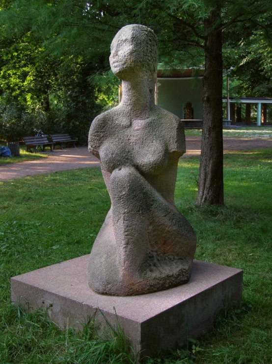 a statue of a seated woman in a grassy park