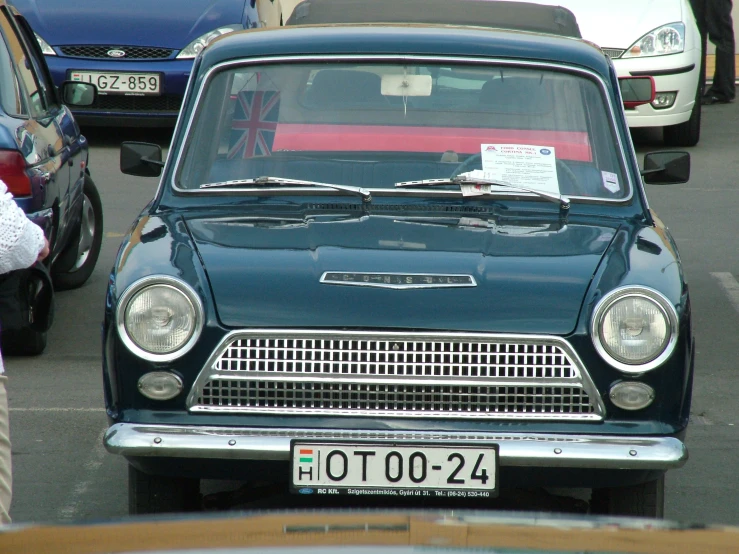 an old car in a parking lot with other cars in the background