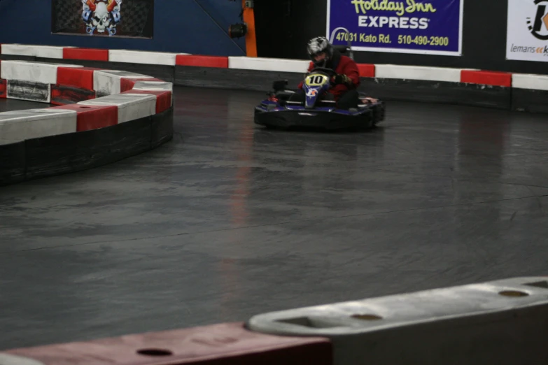 a girl riding on a small bumper car in an indoor racing track