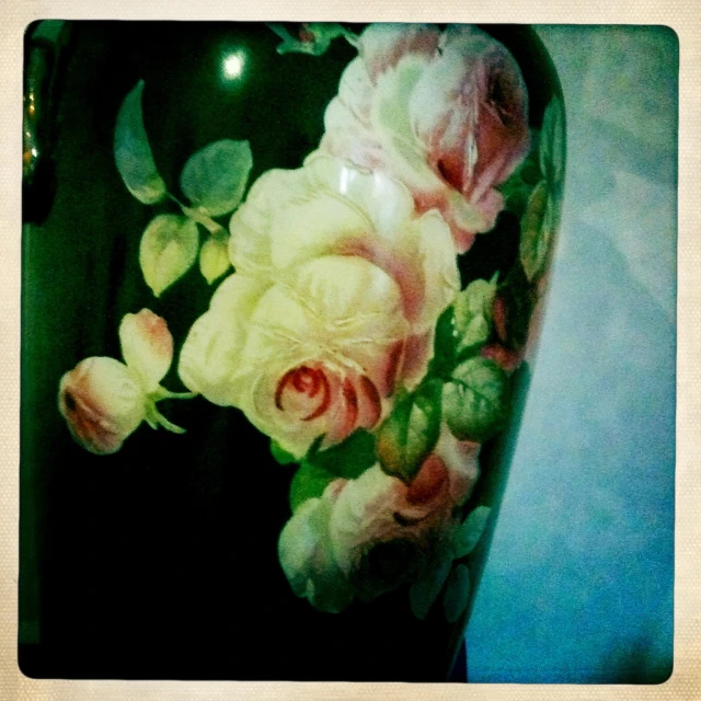 a black vase filled with white roses on a table