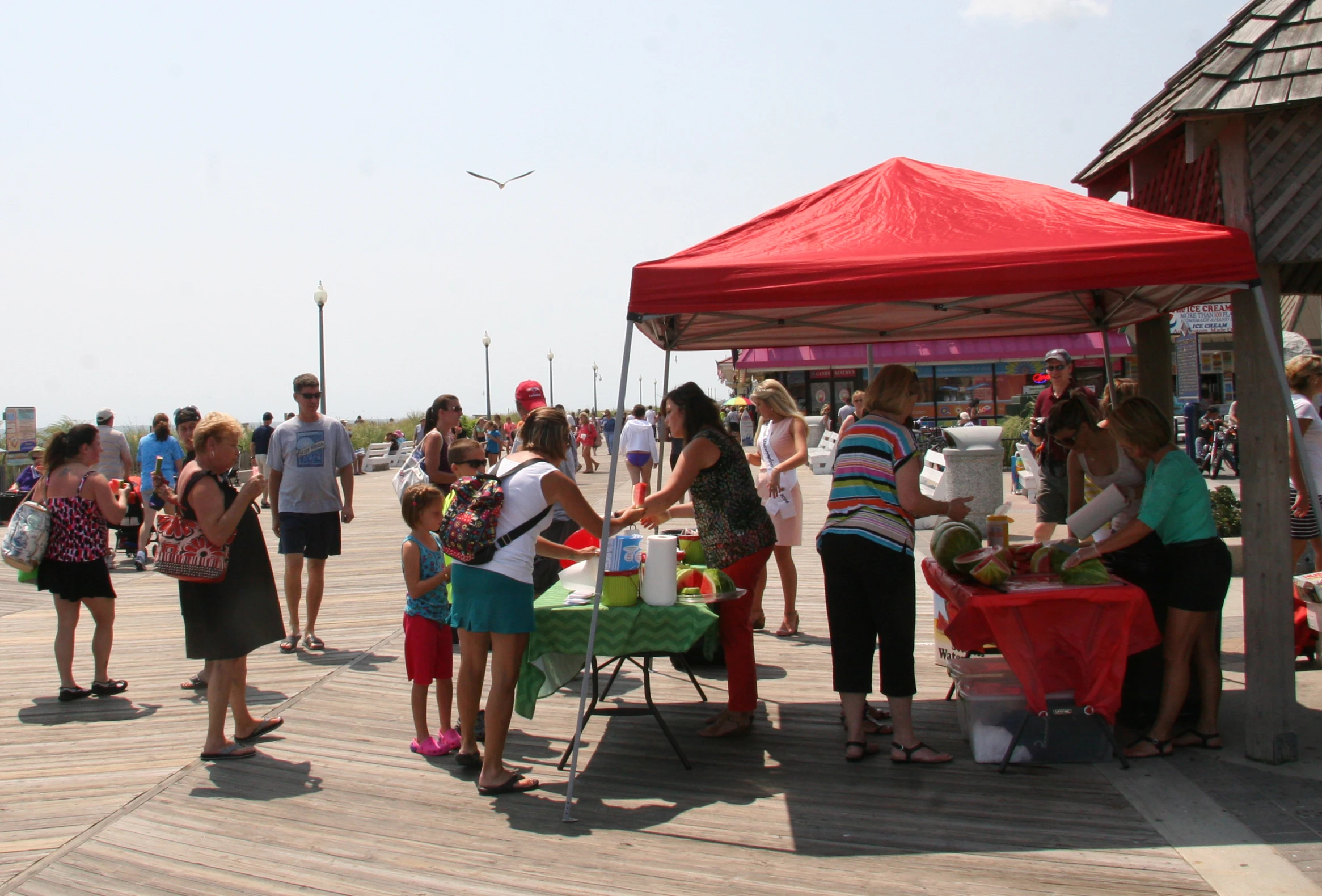 many people standing on a pier near an umbrella