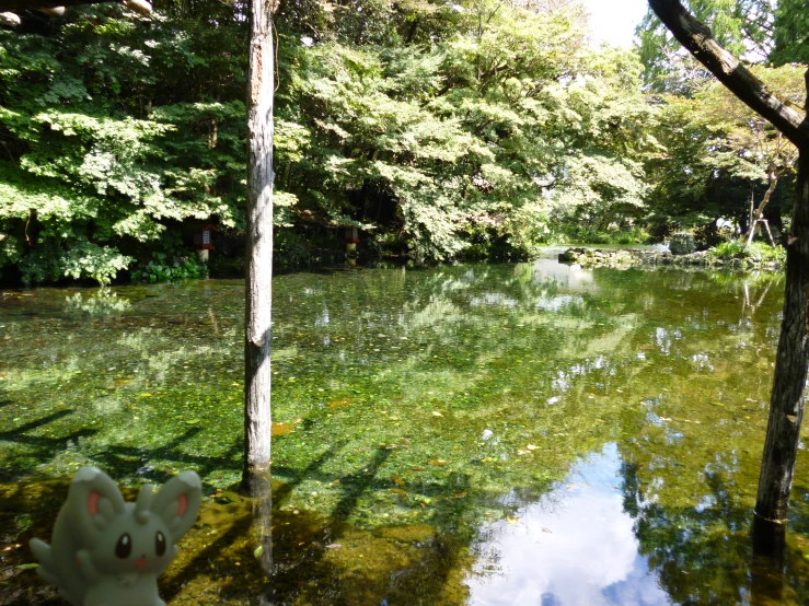 two stuffed elephants stand next to a pond