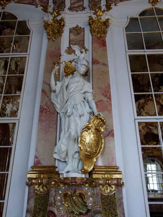 a statue of a lady justice is surrounded by white columns and gold details