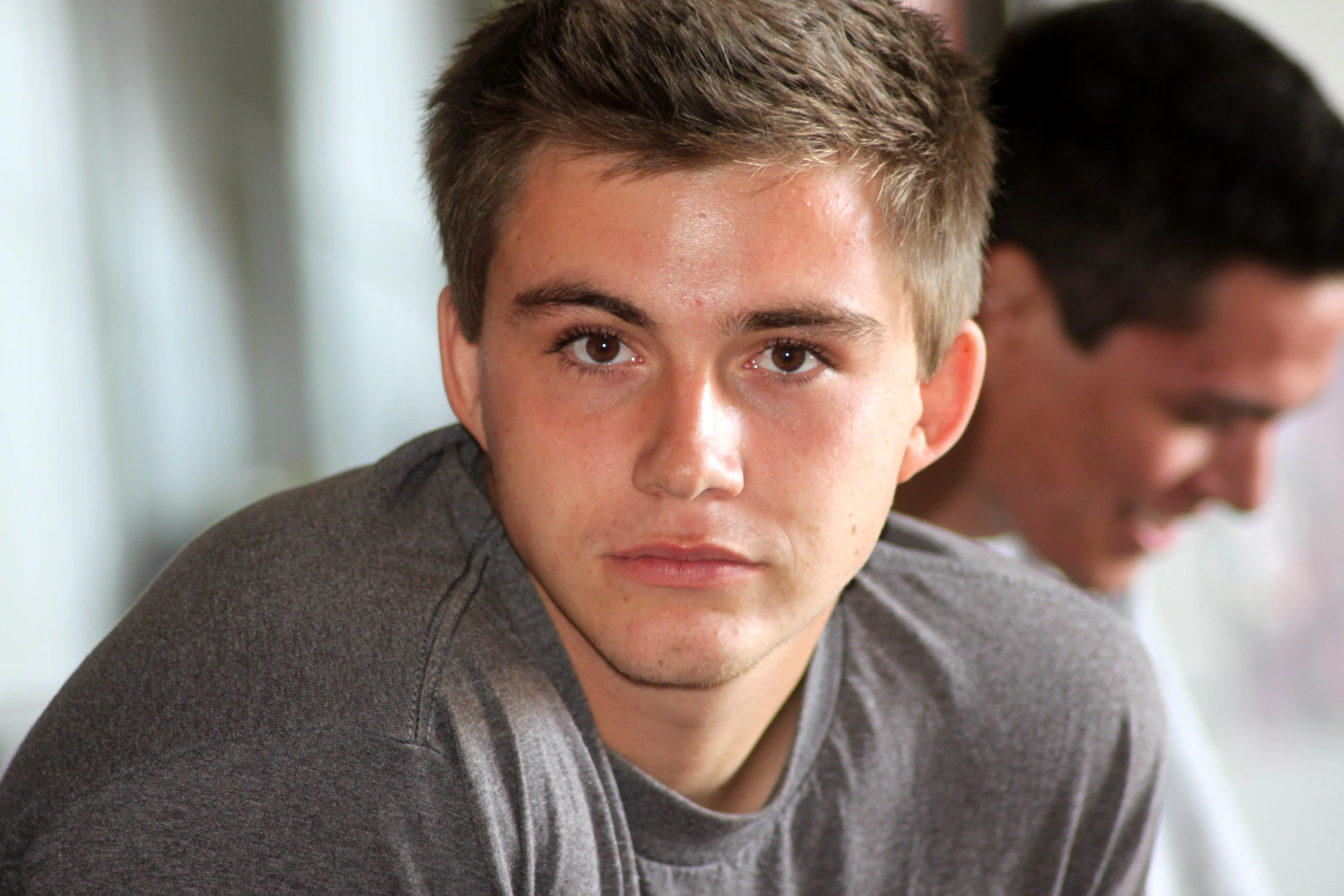 young man looking at the camera, wearing grey shirt