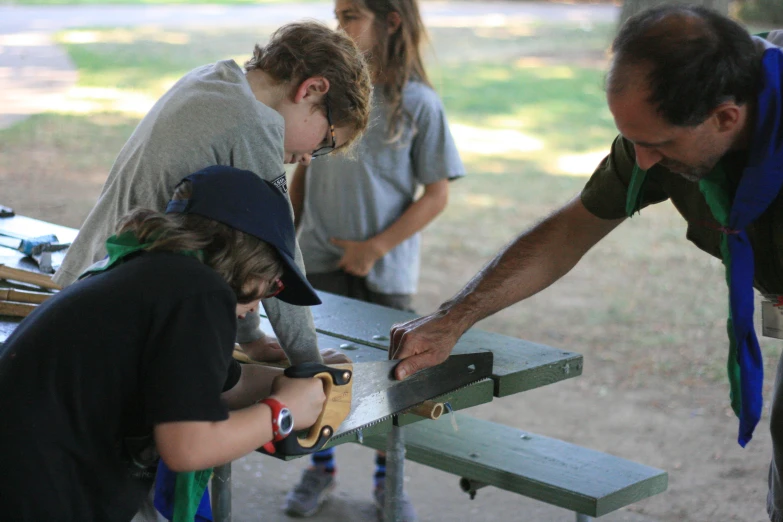 a group of young people are using a tool on a bench