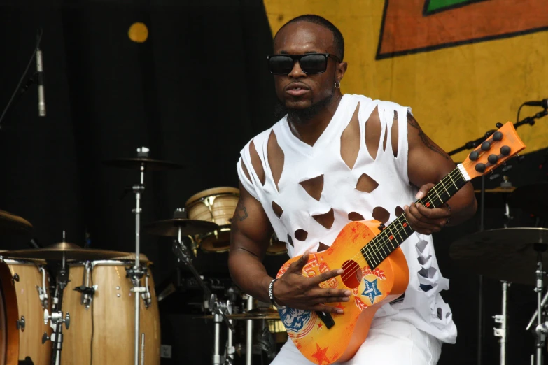 a man playing a guitar in front of a microphone and a drum