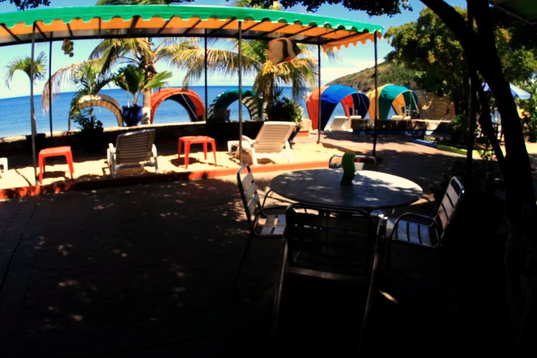 a picnic area next to an ocean with tables and chairs