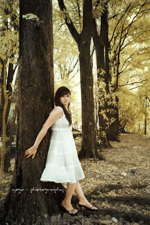 a woman is standing next to a tree