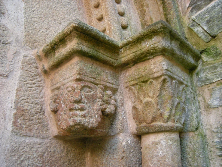 a carved head between two large, old stone pillar