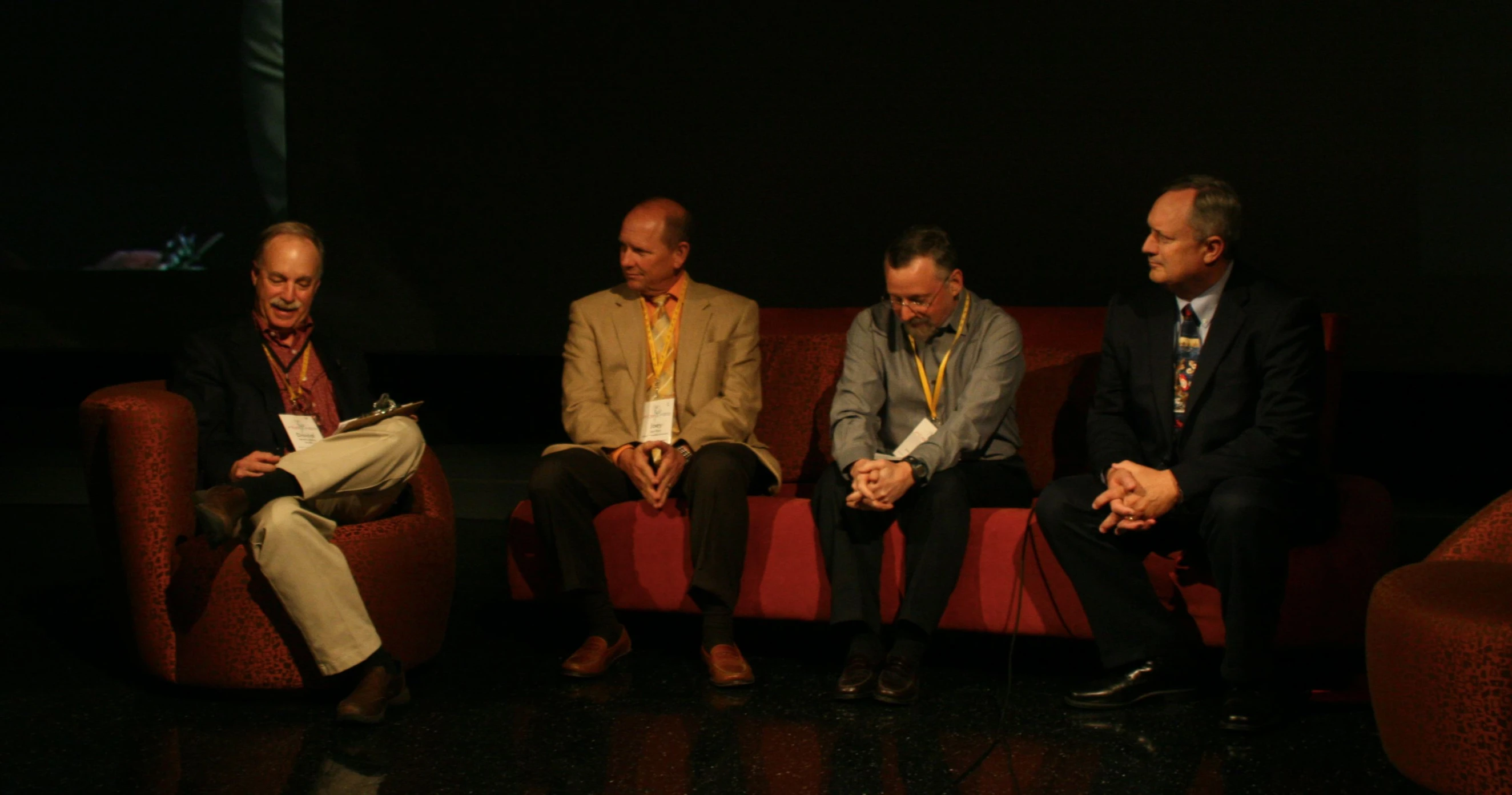 three men and a woman sitting on a red couch