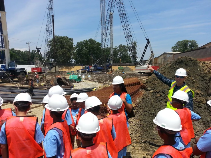 men in hard hats and vests watch construction on site