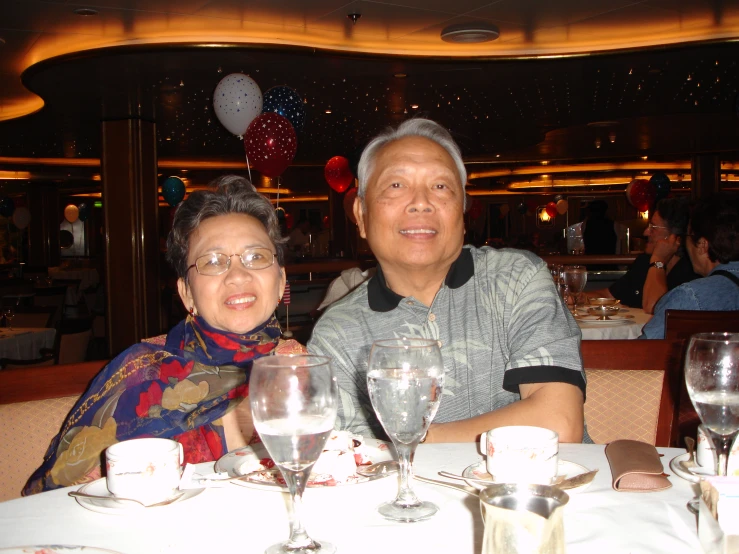 two people are seated at a table with wine glasses and silverware on it