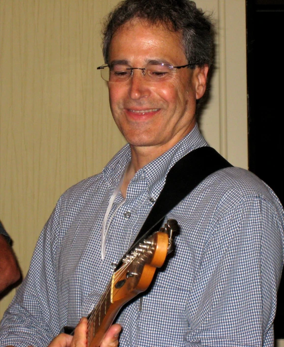 man with glasses and a guitar smiling for the camera