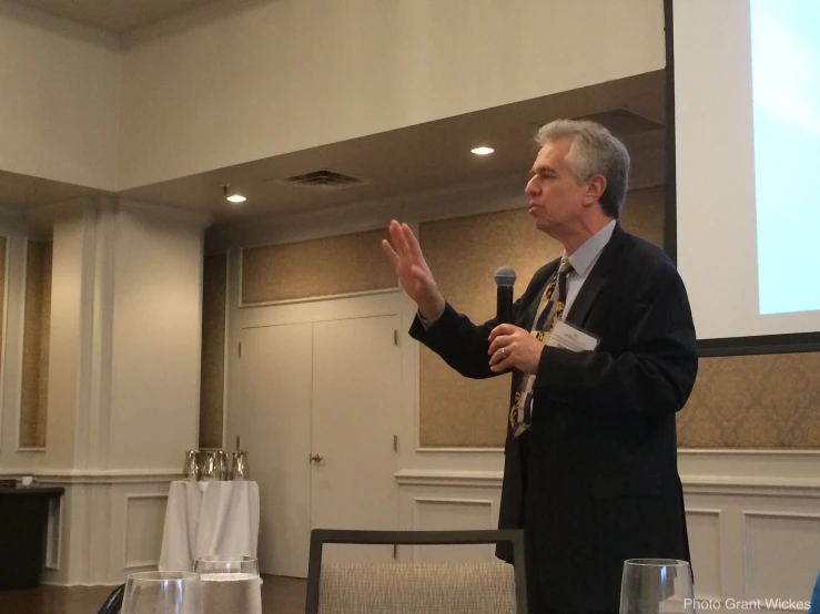 a man in a suit is speaking at a seminar