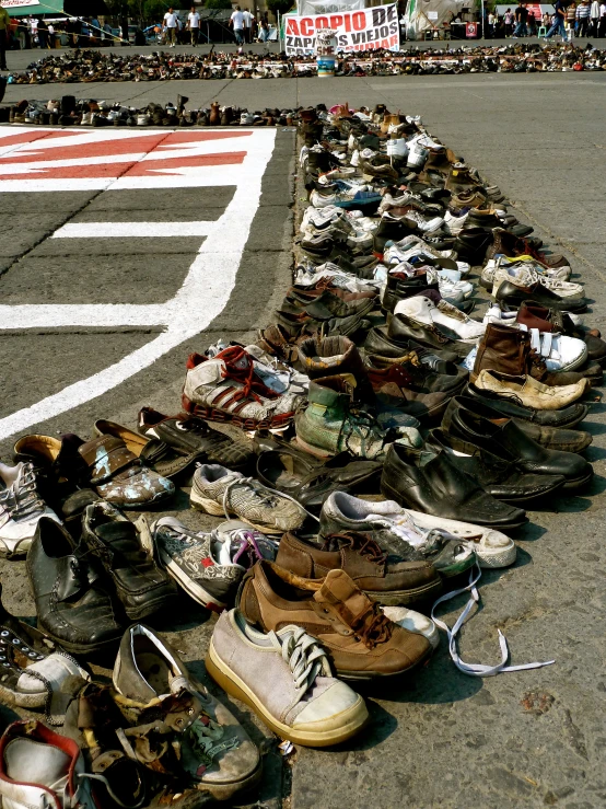 many shoes lay on a track while people stand in the background