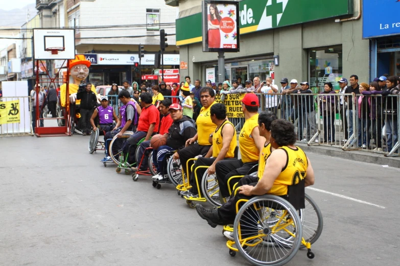 a row of men in yellow uniforms, sitting on wheelchairs