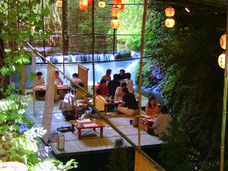 a group of people sitting at tables in front of a waterfall