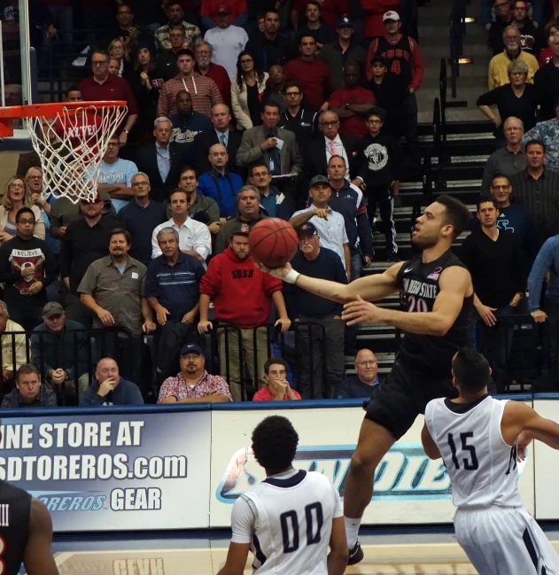 a basketball player jumping in front of an opponent to dunk the ball