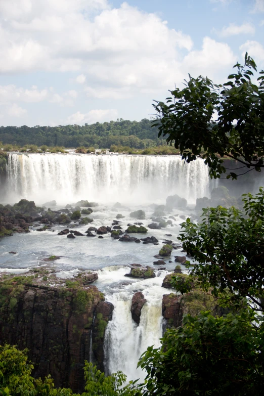 the waterfalls of a body of water with green trees