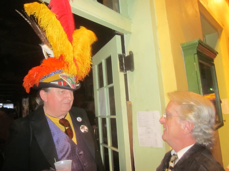 a man wearing a colorful hat in front of a green door