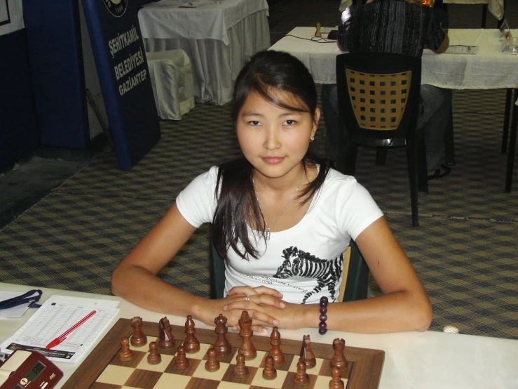 a  sitting at a table looking over some chess pieces