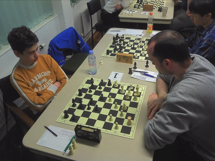 four people sitting at a table playing checkers