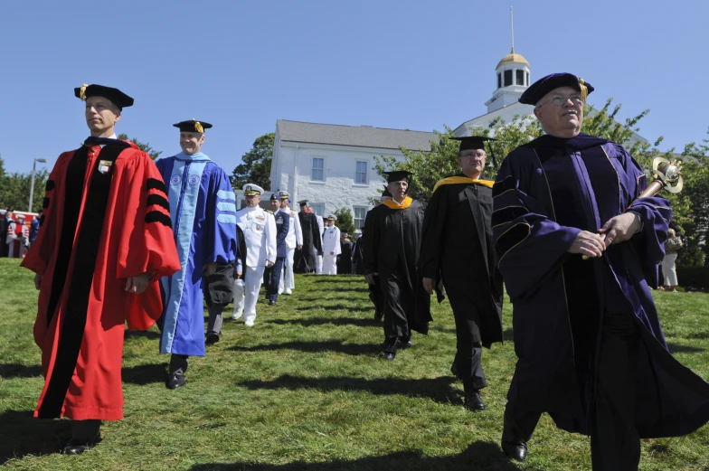 students are walking in the grass in their graduation gowns