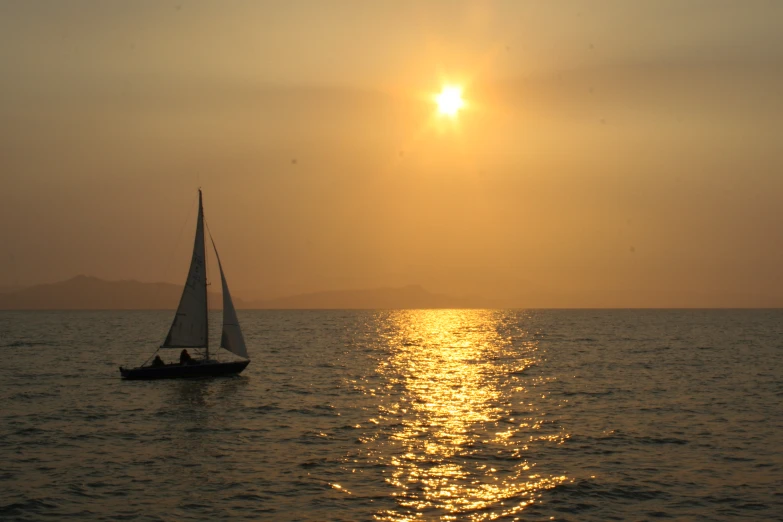 a sailboat is out in the ocean at sunset