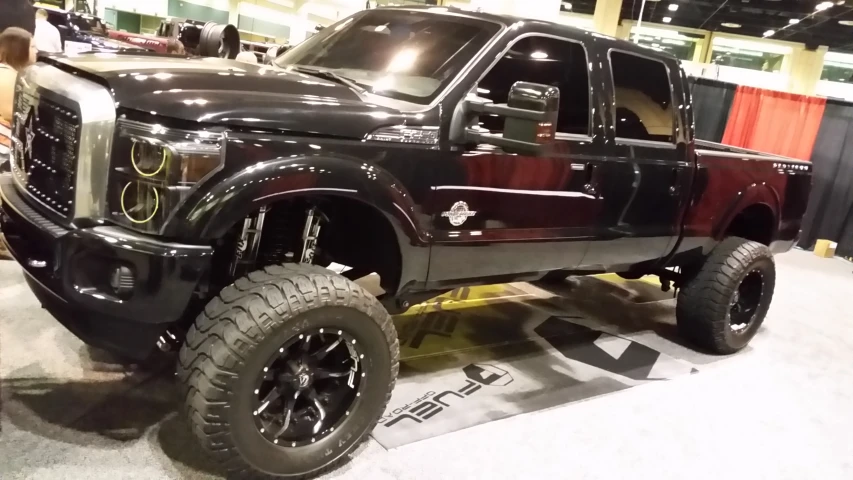 an off - road pickup truck with large tires is displayed at a show