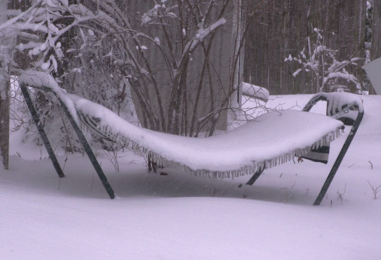 a frozen park bench covered in snow during the winter