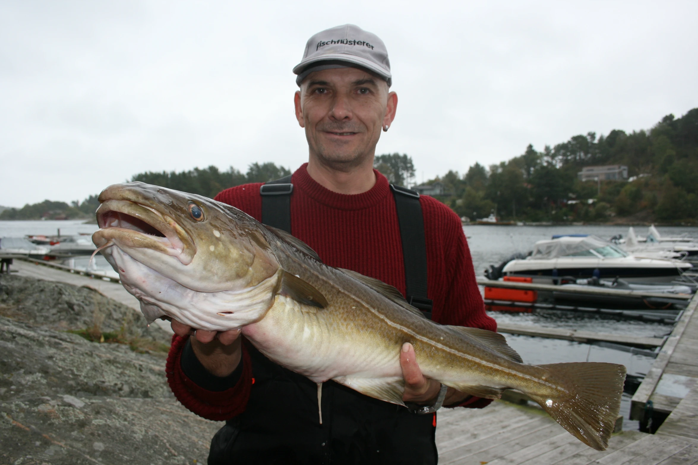 a man holds up a fish at the water