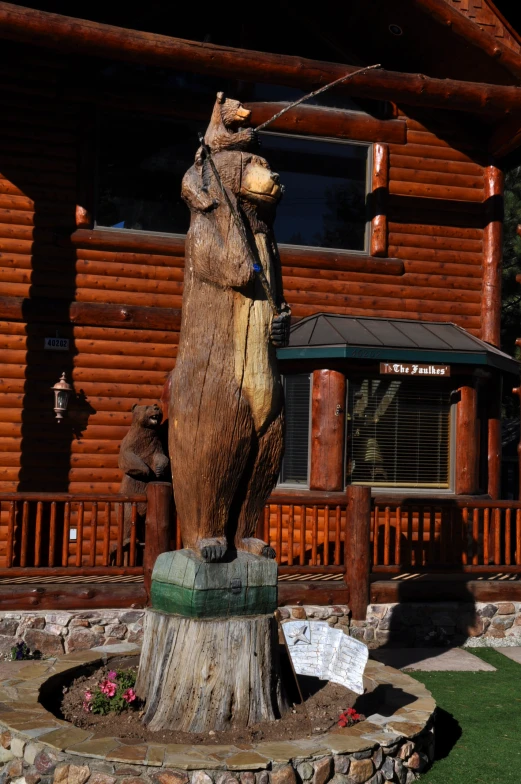 a log bear statue is near a small wooden building